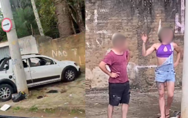 A imagem está dividida em duas partes. À esquerda, um carro branco está fortemente danificado após bater em um muro, com os vidros quebrados e a lateral amassada. O veículo está parado em frente a um muro pichado, onde se lê "NÃO T...". Há lixo espalhado no chão. À direita, uma mulher trans, usando um top roxo e shorts jeans, gesticula com a mão levantada enquanto discute com um homem de camiseta vermelha e bermuda escura. Ambos estão em frente a uma parede de tijolos aparentes.