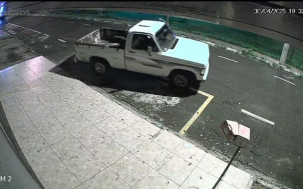 Imagem de uma câmera de segurança mostra uma caminhonete D20 branca, modelo antigo, sendo levada por um criminoso durante a noite. O veículo aparece já em movimento, saindo de uma vaga na rua Porto Velho, no Jardim Brasilândia, em Franca. A imagem é noturna, com iluminação artificial refletindo no asfalto molhado. À direita, aparece uma estrutura metálica inclinada com uma caixa de papelão, e ao fundo é possível ver a calçada e parte de uma pista com faixa amarela
