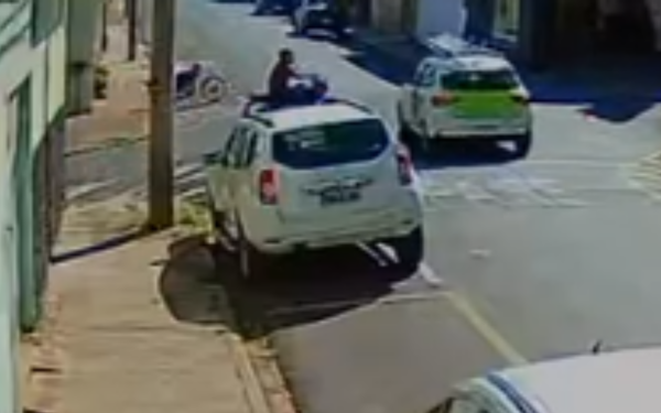 Imagem de câmera de segurança mostra um cruzamento no Centro de Franca. Um carro branco aparece parado no canto da rua, enquanto ao fundo é possível ver um motociclista caído ao lado da moto no asfalto, após o acidente.